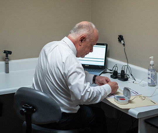 Dr Vehr in his office configuring a pair of hearing aids. 