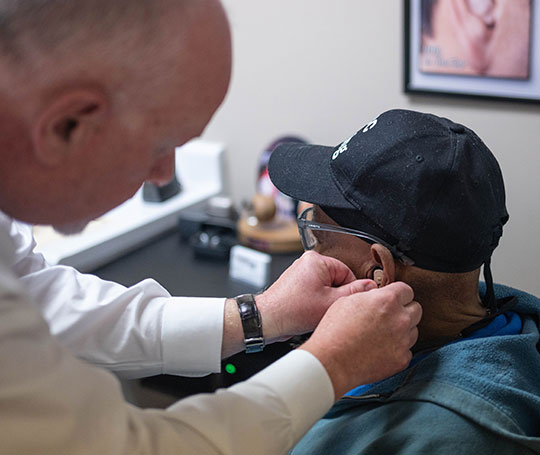 Dr. Vehr fits a patient with a hearing aid.