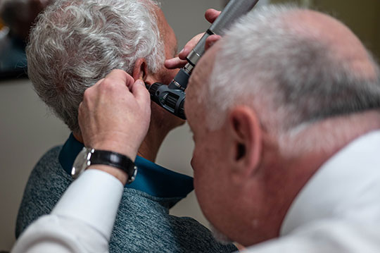 An audiologist uses an otoscope to look in a patient's ear.