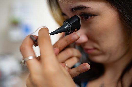 An audiologist looking at a hearing aid