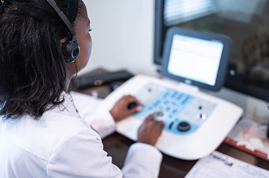 TaRonda Clark, Au.D. working the controls of a hearing booth.